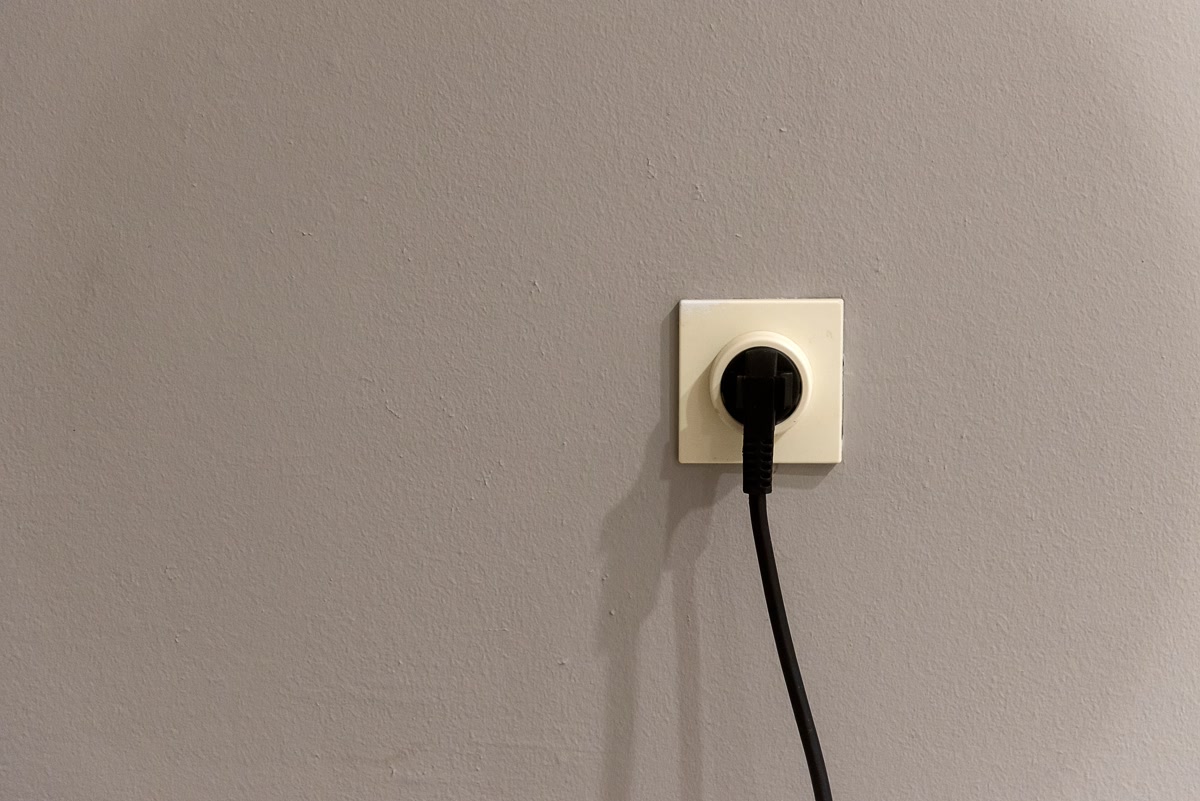 Electrical plug in wall outlet representing smart plug usage for bathroom hair tool safety automation