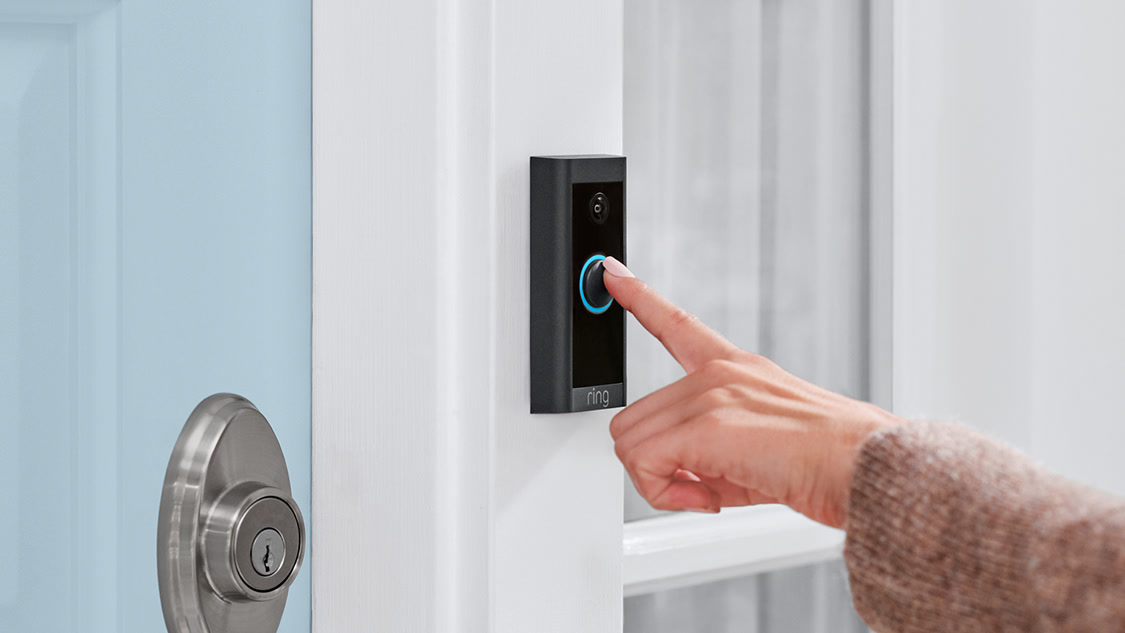 Person pressing Ring video doorbell on door frame