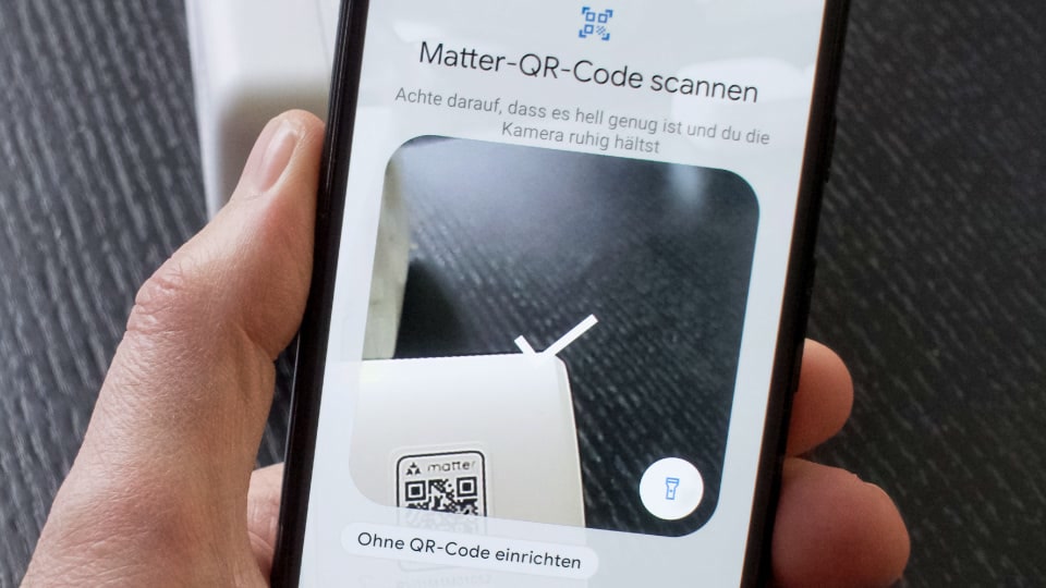 Smartphone scanning a Matter QR code next to a smart home sensor device