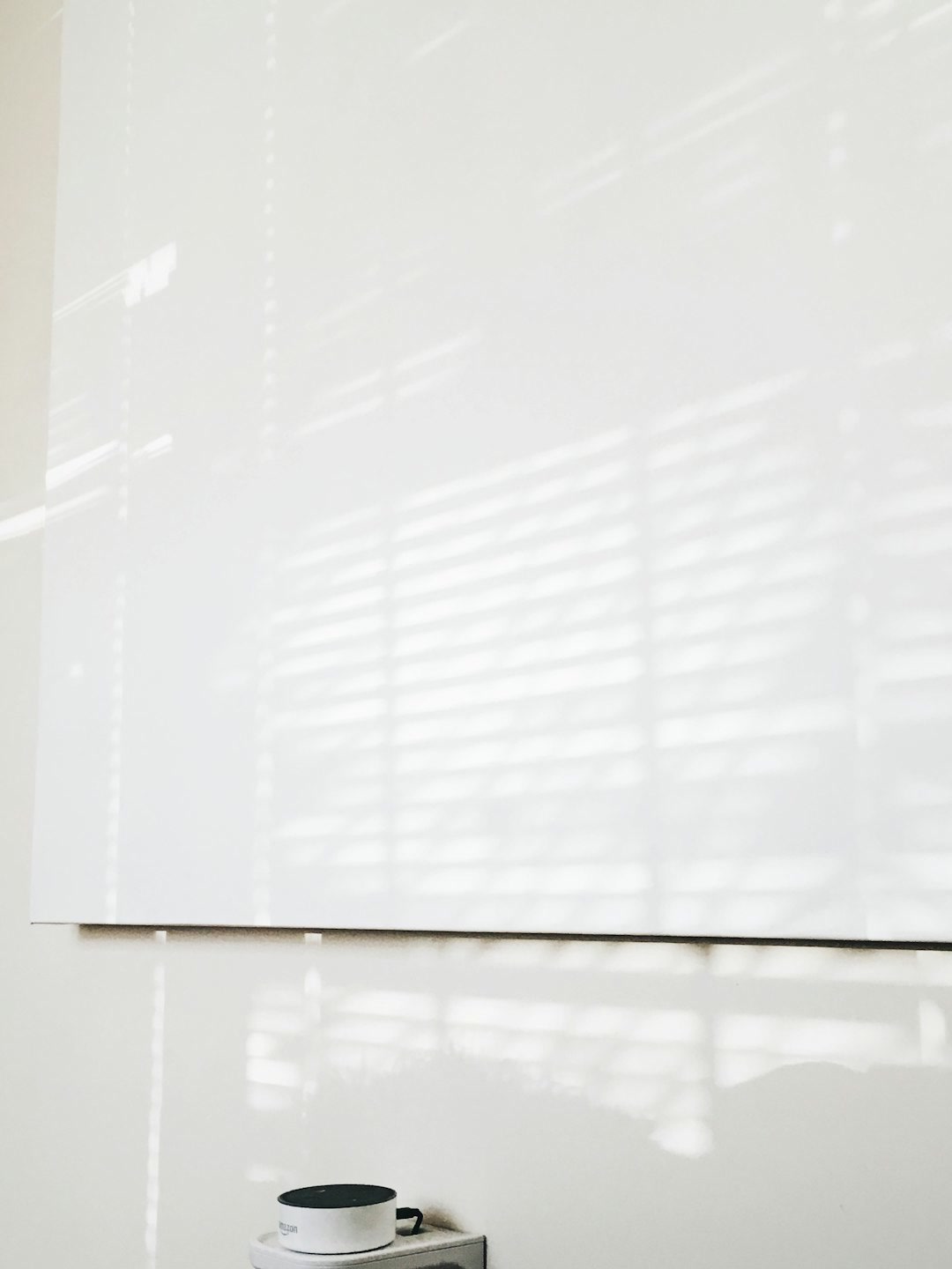 Small solar panel mounted on a window frame powering a smart blind motor, bright daylight