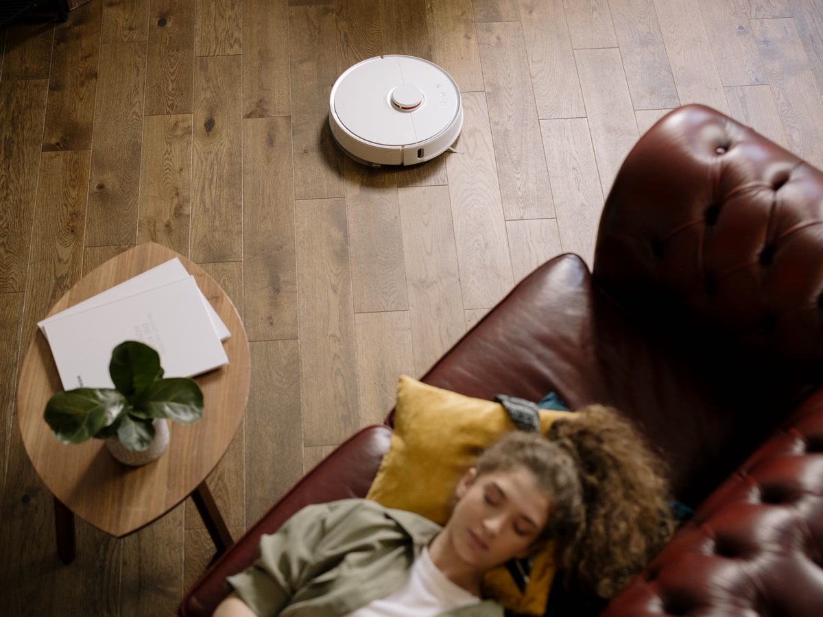 Modern robot vacuum cleaning hardwood floor in a bright living room