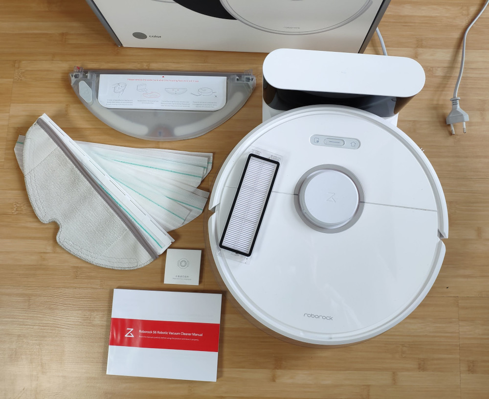 Robot vacuum and its replacement accessories laid out on a table