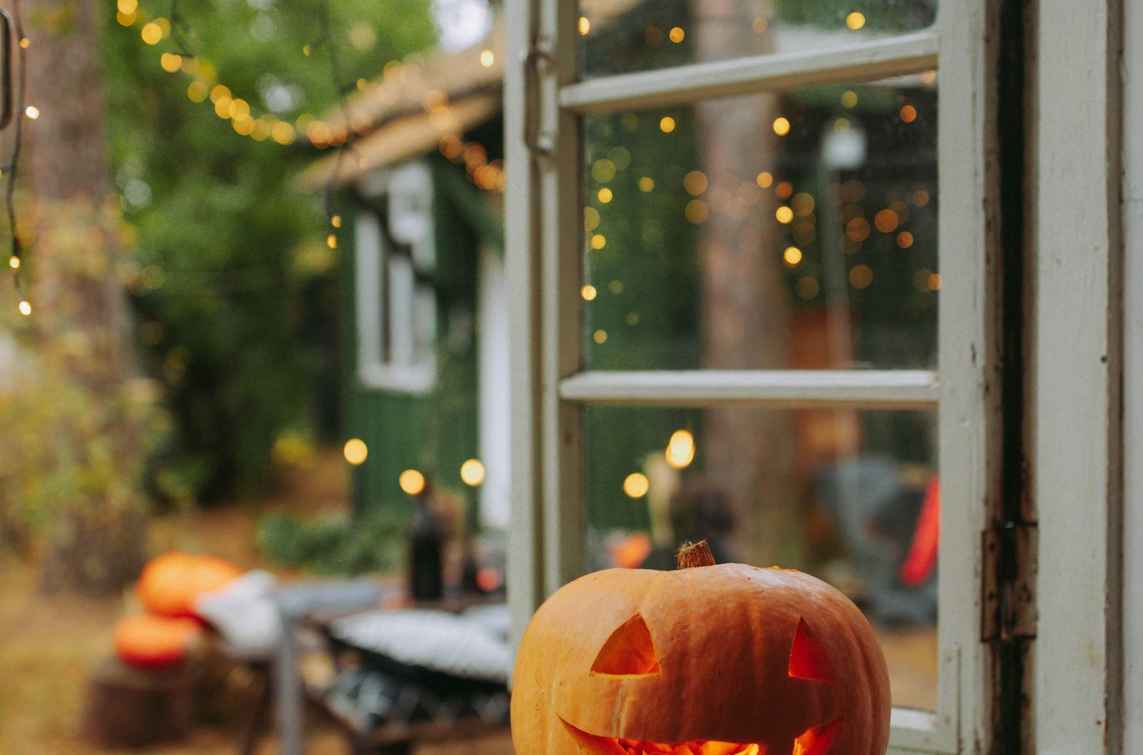 Jack-o-lantern glowing by a window with string lights