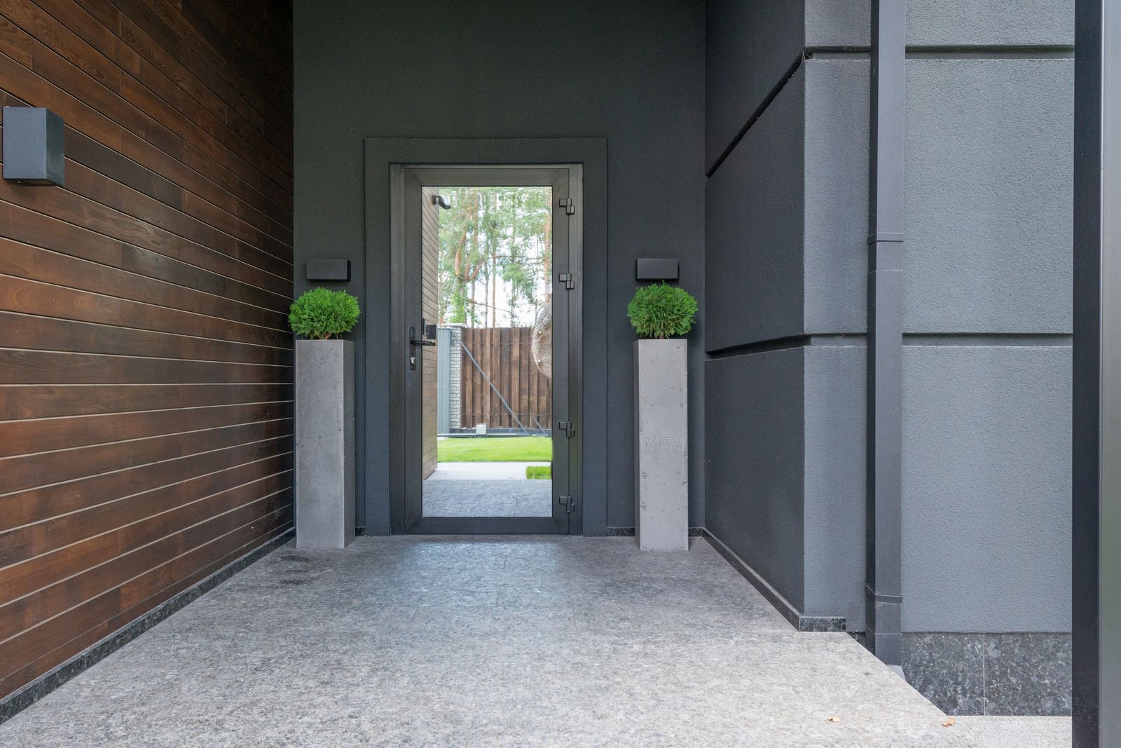 Modern home entrance with a glazed front door and planters
